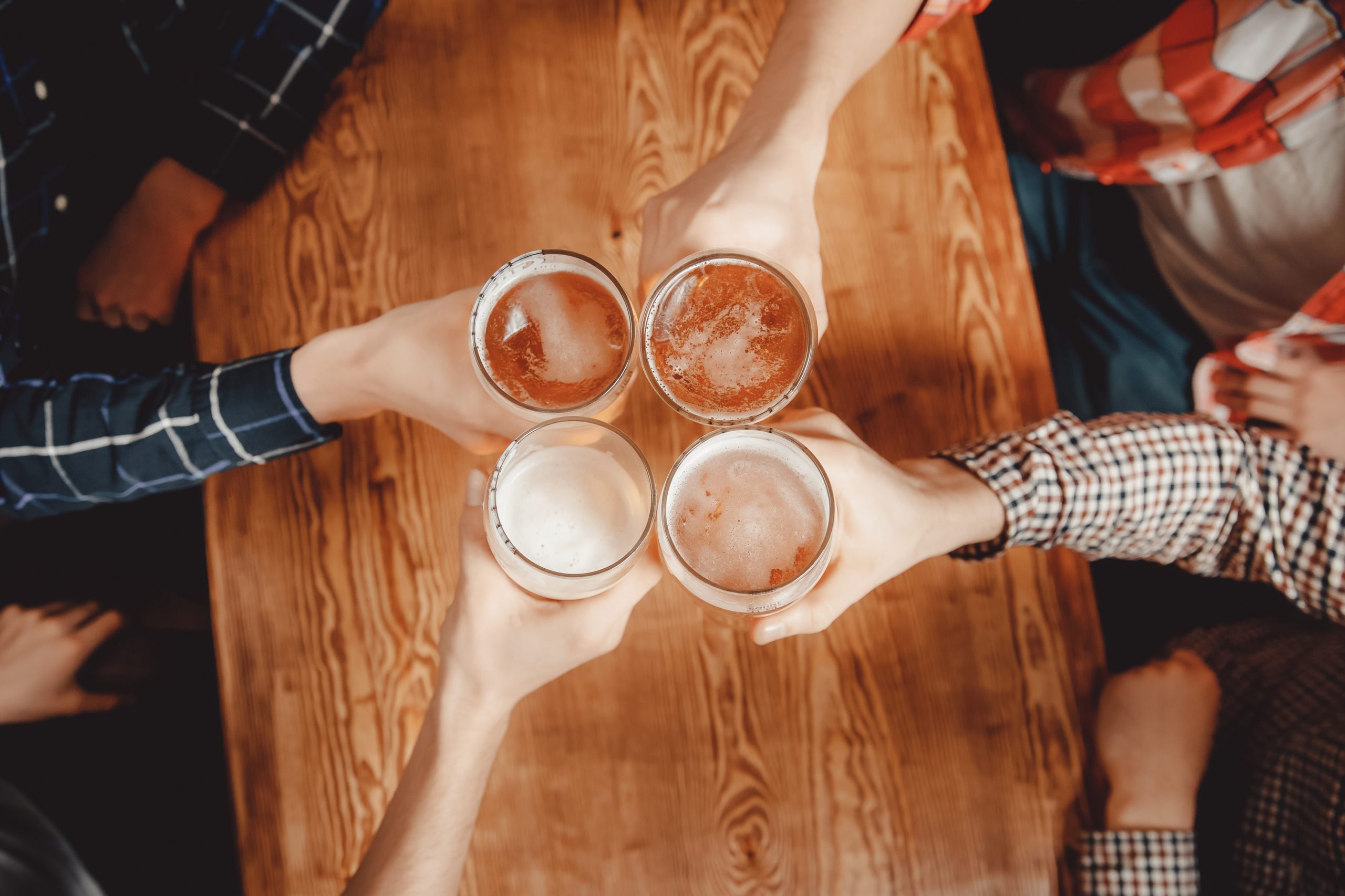 Cheerful and happy old friends are drinking draft beer at pub ba