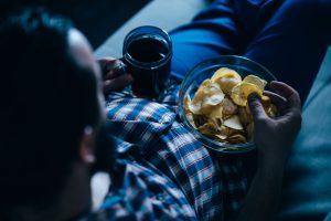 Man eating takeout food and watching movie with a beer